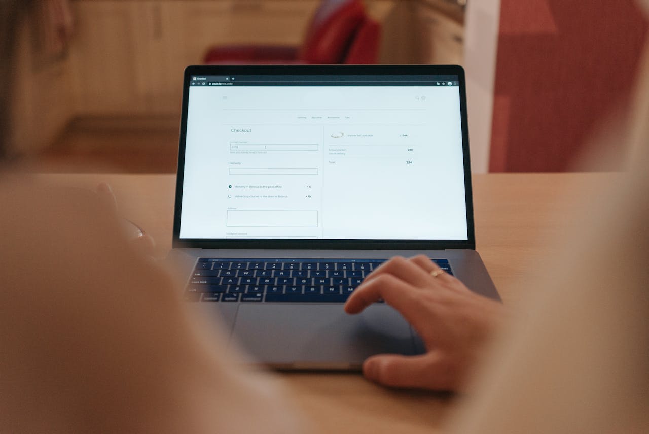 Offerings Close-up of a person navigating online checkout on a laptop screen in a cozy indoor setting.